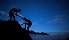 A picture of a person helping another person up a mountain symbolizing the willingness to help one another.